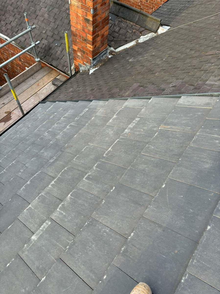 New slate tiles dressed neatly into a brick chimney stack with fresh lead flashing