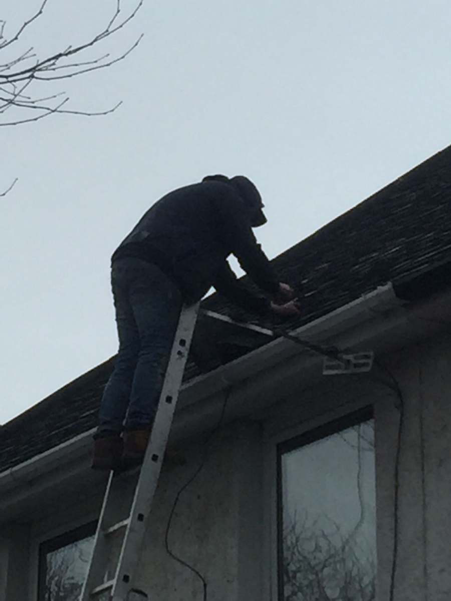 Close-up of a roofer repairing a roof edge from a ladder