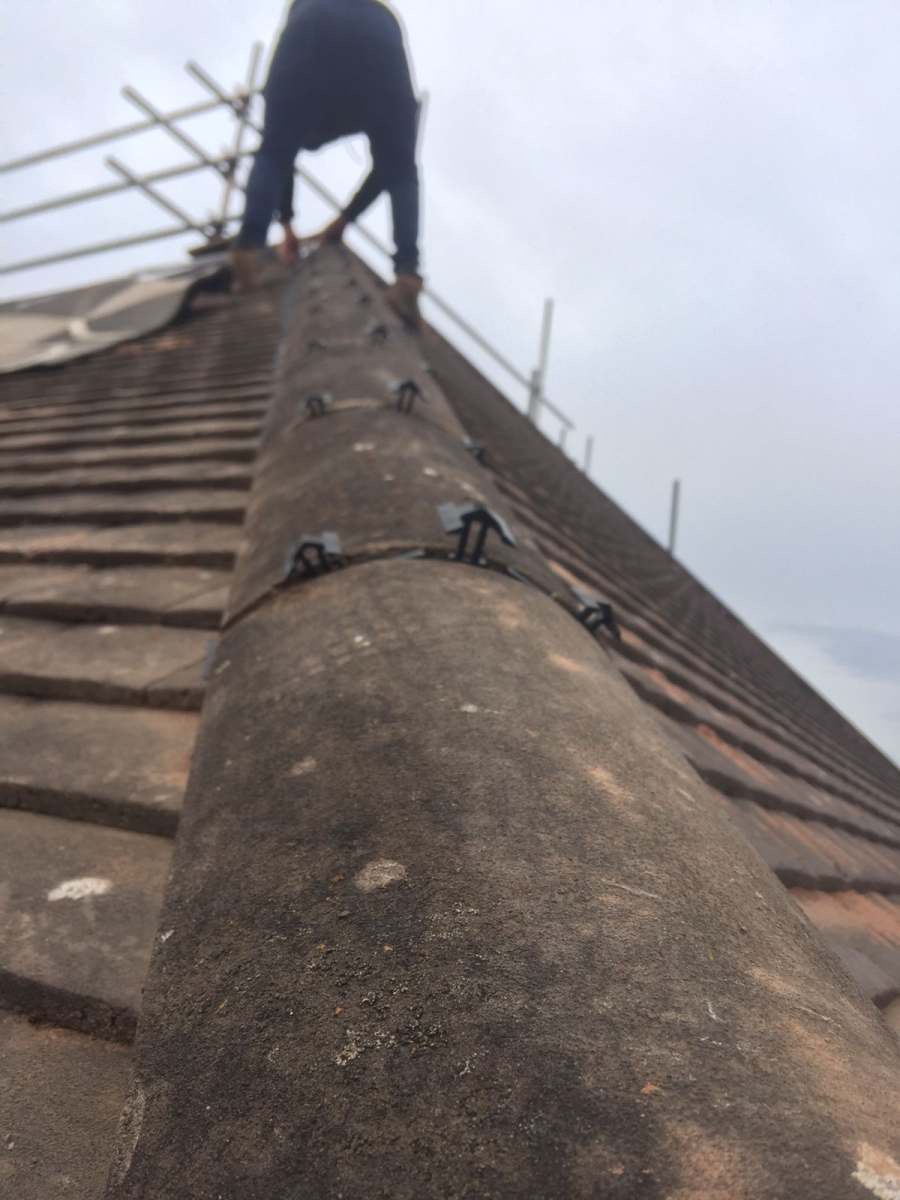 Installing a mechanically fixed dry-ridge system along a tiled roof peak