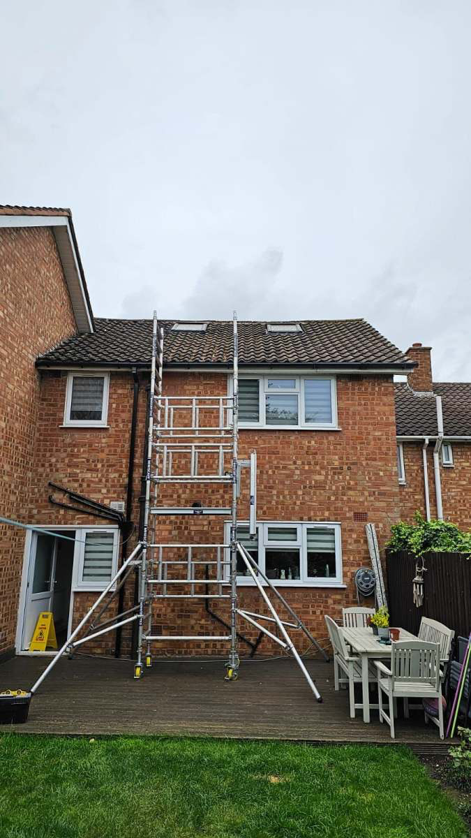 Scaffold tower erected at the rear of a brick house for safe roof access