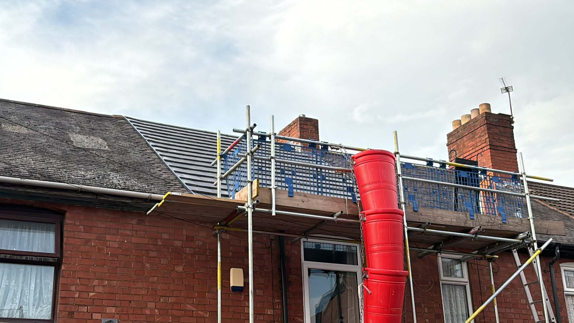 GS Roofs Ltd roofer working on a brick chimney stack from a scaffold platform